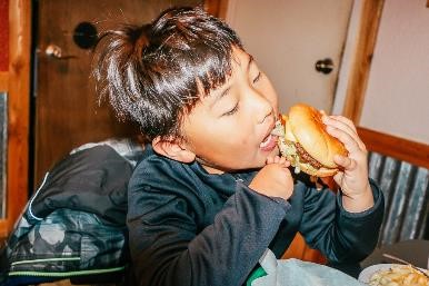 How to plan your family vacation on a budget|Little boy with limb difference eating a cheesburger
