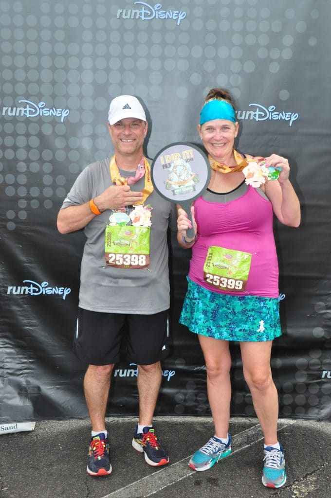 Disney Wine and Dine Half Marathon Weekend - Your Questions Answered|Run Disney Ripped Jeans and Bifocals Smiling couple in running clothes in front of run Disney sign