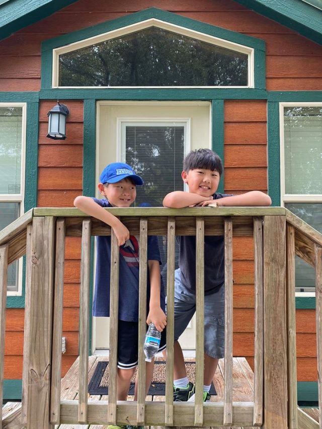 Two boys on the porch of a tiny cabin