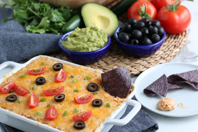 refried bean dip on the table with avocados and olives