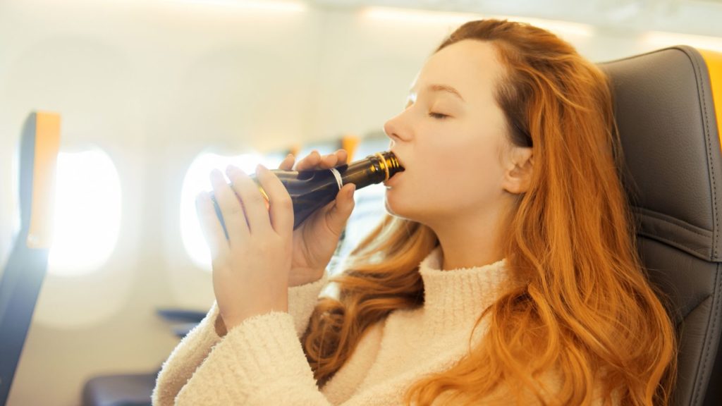 Woman drinking on a plane.