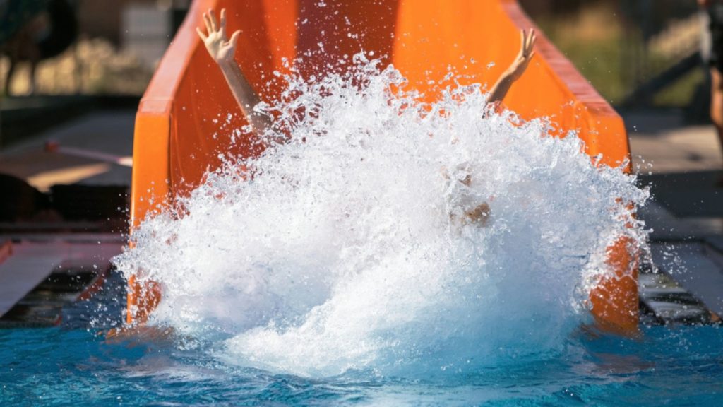 Child coming down an orange water slide.