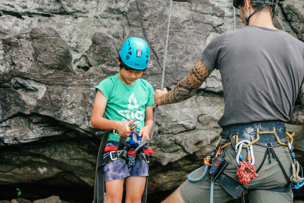 Child in helmet in rock climbing gear with instructor