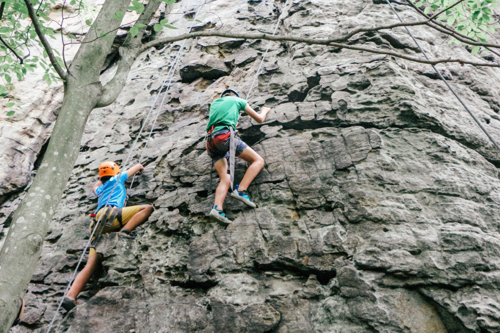 Two kids climbing a rock