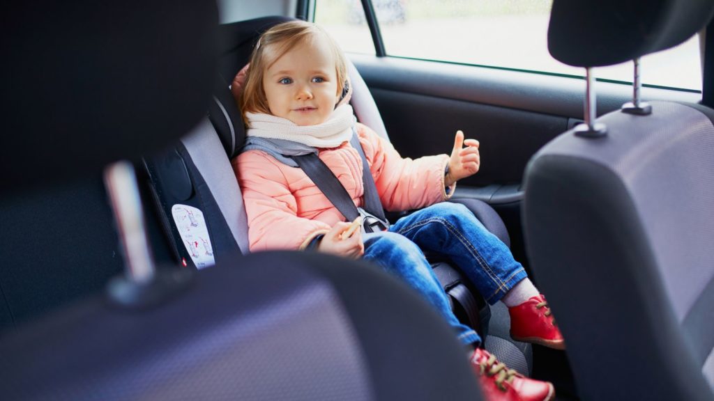 Girl in car seat family travel.