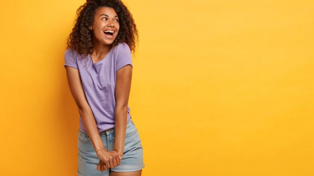 Woman wearing purple tee shirt and denim shorts.