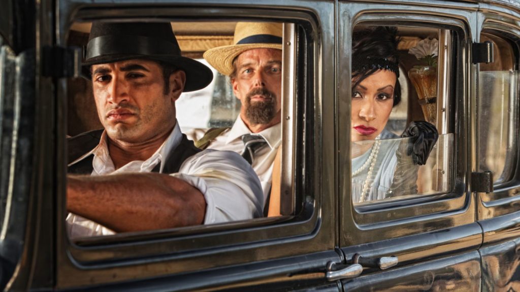 1930s characters riding in vintage car.