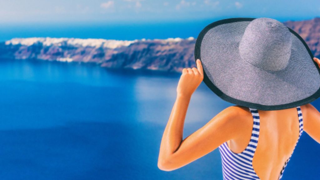 Woman in hat next to ocean.