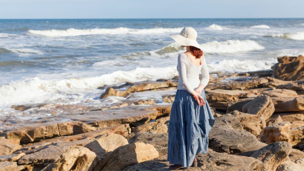 Pale woman standing by the beach.