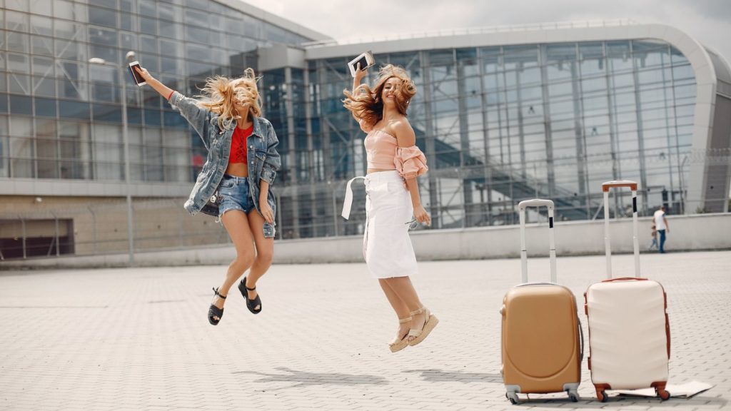 Two woman at the airport with luggage.