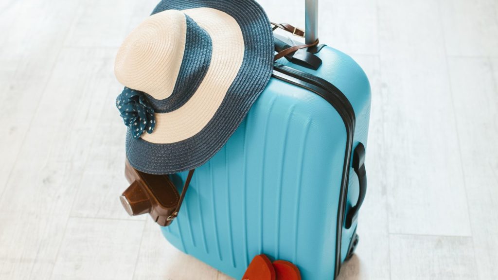 Blue suitcase with hat on top.