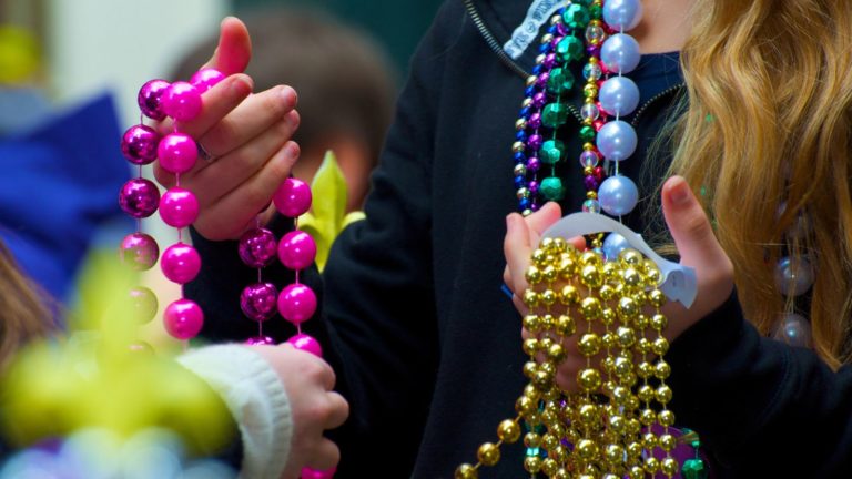 Girl holding Mardi Gras beads.